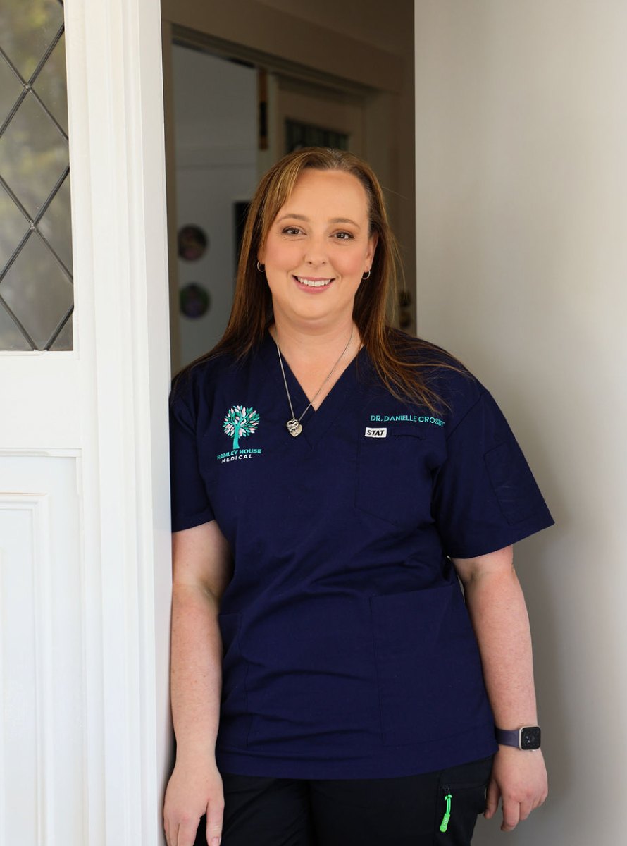Dr Danielle Crosby in navy scrubs, standing in a doorway at the clinic
